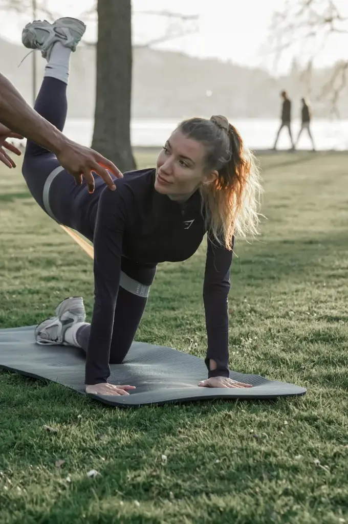 Personal Trainer Adil Semdaji assisting female client glute hamstring resistance band strength training