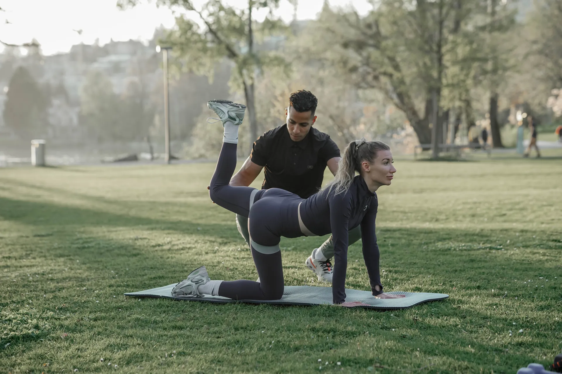 Personal Trainer session outdoors using gym elastic bands targeting buttocks and upper legs strength training