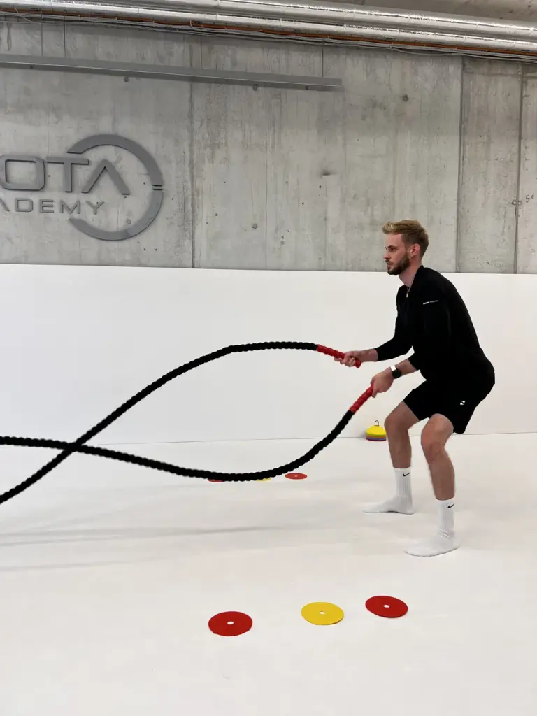 Personal Trainer male client heavy rope training indoor session high intensity functional workout