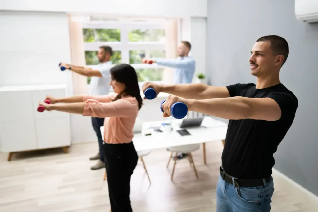 Employee wellness programs office workout session with four staff members using hand weights